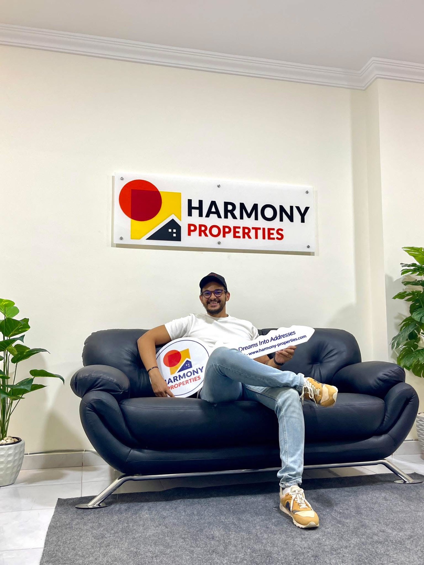 Yehia Hafez, founder of Harmony Properties, seated with the Harmony Properties key and office sign visible